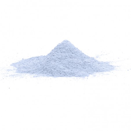 Una pequeña pila cónica de polvo fino de color azul claro se asienta sobre una superficie blanca y lisa, sobre un fondo blanco l