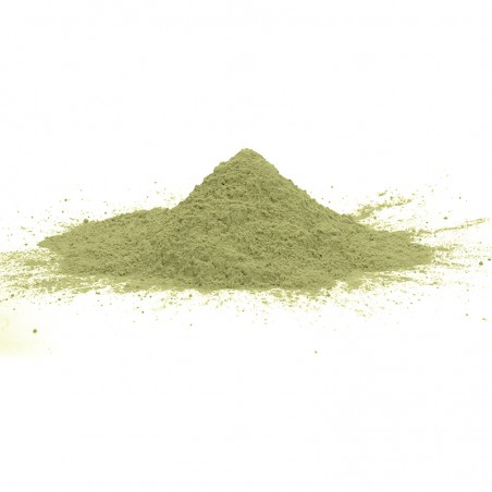 Polvo verde que forma un pequeño montículo, apoyado sobre una superficie plana y blanca, con finas partículas dispersas a su alr