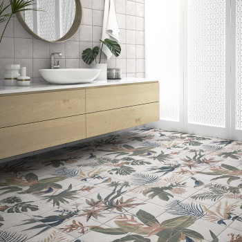 Azulejos com motivos florais cobrem o chão do banheiro, representando várias plantas tropicais. Uma penteadeira de madeira com p
