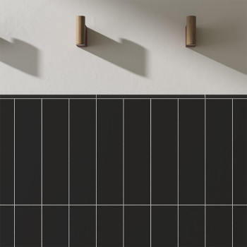 Vertikale schwarze Fliesen mit weißen Fugenlinien sind vor einer glatten weißen Wand platziert. Zwei zylindrische Holzhaken werf