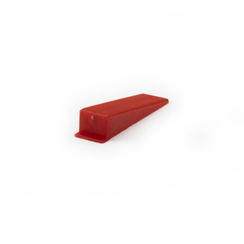 Un arrêt de porte rouge en forme de coin repose sur une surface blanche unie, légèrement inclinée vers le haut, sans texte ni ma