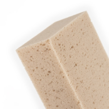Una esponja rectangular de color beige con una textura porosa se asienta sobre un fondo blanco liso.