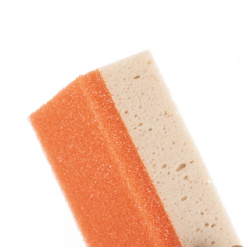 Una esponja de limpieza rectangular tiene un lado de fregado de color naranja grueso sobre una capa absorbente de color beige, s