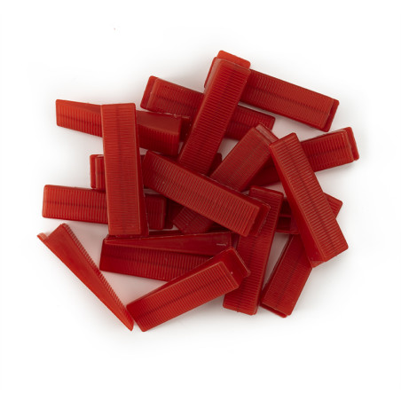 Les peignes rectangulaires rouges sont empilés en tas dispersés sur une surface blanche unie.