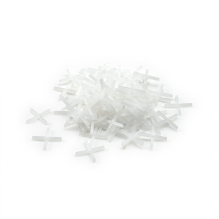 Ein Stapel weißer Kunststofffliesenabstandshalter bildet einen losen Hügel vor einem schlichten weißen Hintergrund.