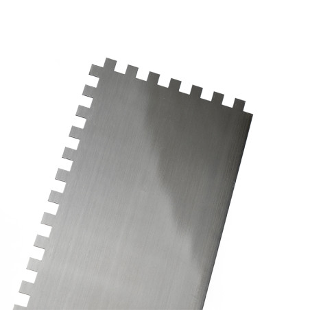 Una llana dentada de metal con dientes cuadrados uniformemente espaciados, diseñada para esparcir adhesivo, se coloca sobre un f