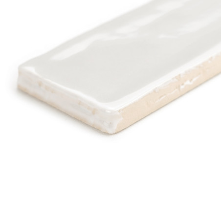 Um revestimento cerâmico retangular é mostrado com uma superfície branca brilhante, apoiada sobre um fundo liso e neutro.