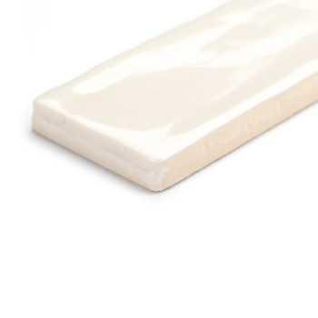 Eine rechteckige Keramikfliese liegt flach und zeigt eine glänzende cremefarbene Oberfläche mit weichen, wellenförmigen Mustern.