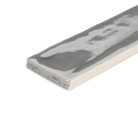 Le carreau de céramique rectangulaire, présentant une surface grise chinée brillante, repose à plat sur un fond blanc uni.