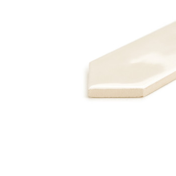 Um azulejo brilhante, esbranquiçado e pontiagudo repousa sobre uma superfície branca, refletindo a luz sutilmente em um ambiente