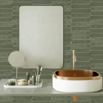 Un lavabo blanc avec une vasque en cuivre repose sur un comptoir gris avec des articles de toilette, sous un miroir rectangulair