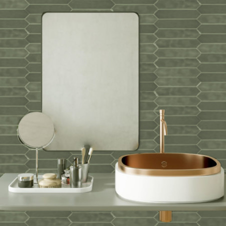 Un lavabo blanc avec une vasque en cuivre repose sur un comptoir gris avec des articles de toilette, sous un miroir rectangulair