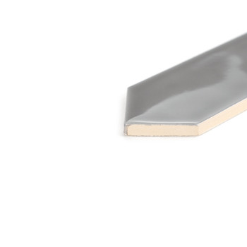 Un azulejo gris brillante colocado sobre una superficie blanca, cortado para revelar su interior color crema, con un borde hexag