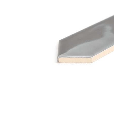 Azulejo cinza brilhante posicionado sobre superfície branca, recortado para revelar seu interior de cor creme, com borda hexagon