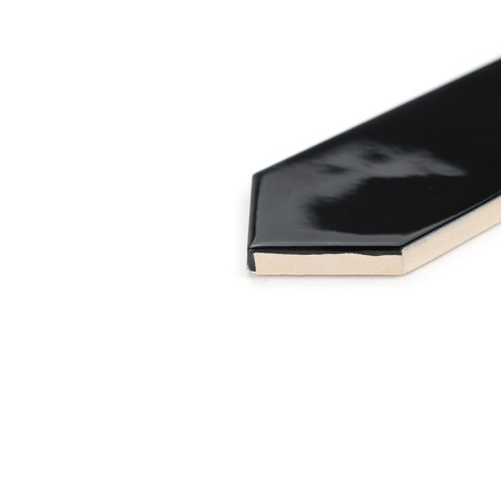 Un carreau de céramique noir brillant de forme pentagonale repose sur une surface blanche, affichant son bord incliné et sa fini