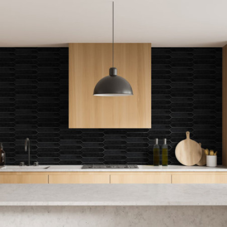 Über einer Küchentheke aus hellem Holz hängt eine graue Lampe. Schwarze geometrische Fliesen bilden eine moderne Rückwand, einge