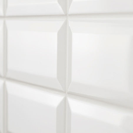 White glossy ceramic tiles form a grid pattern, reflecting light, creating a clean and modern appearance in an interior setting.