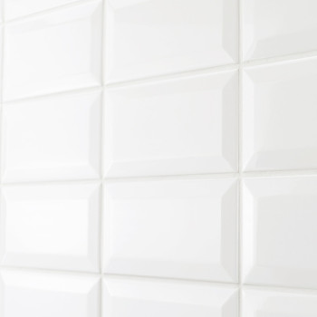 Azulejos rectangulares blancos y brillantes dispuestos en forma de cuadrícula, que reflejan la luz en un ambiente de baño o coci