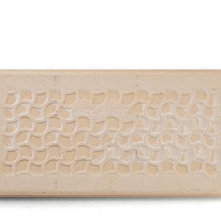 Un azulejo beige rectangular muestra un patrón repetitivo de semicírculos entrelazados. En el centro, un texto tenue dice: `MADE