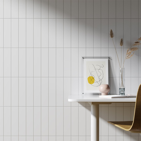 Een wit betegelde muur vormt een strak decor voor een minimalistische werkruimte, met een ingelijste abstracte tekening, een vaa