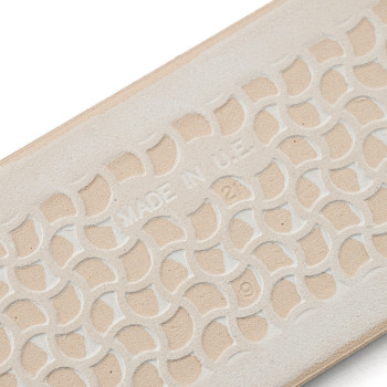 Una suela de goma beige presenta un patrón geométrico entrelazado en relieve con el texto `MADE IN U.S.A.` grabado en el centro.