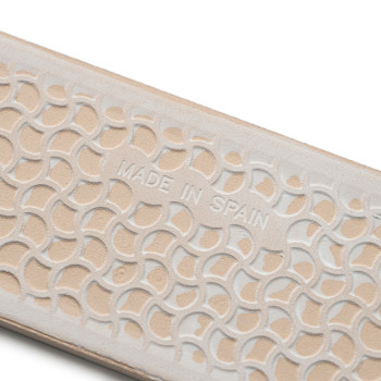 Beige strukturierte Oberfläche mit überlappenden Halbkreisprägungen mit der Aufschrift „MADE IN SPAIN“, die auf der Unterseite e