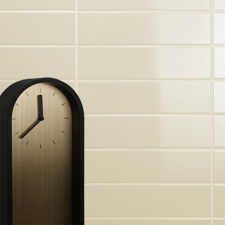 Un reloj minimalista con marco negro no muestra números, solo marcas de hora negras, sobre un fondo de pared de azulejos beige. Un reloj minimalista con marco negro no muestra números, solo marcas de hora negras, sobre un fondo de pared de azulejos beige.