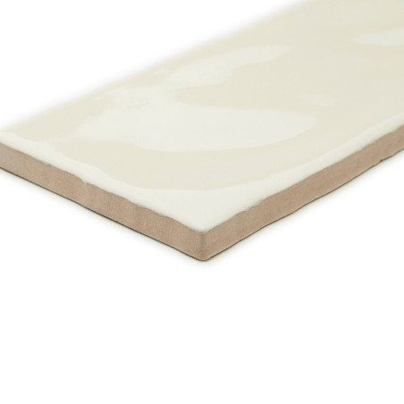 Un carreau de céramique rectangulaire avec une surface blanc cassé brillant et des bords biseautés est isolé sur un fond uni.