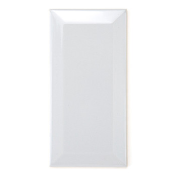 Un carreau rectangulaire blanc brillant reflète la lumière, soulignant sa surface lisse, aux bords légèrement biseautés, sur un 