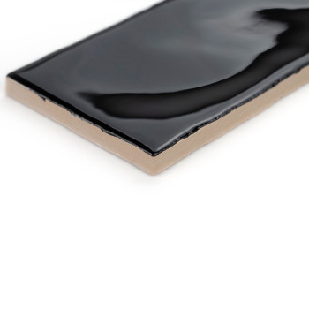Un carreau de céramique rectangulaire présente une surface noire brillante, présentant de légères ondulations, sur un fond blanc