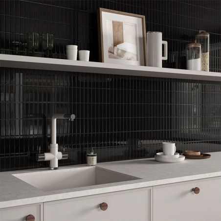 Una encimera de cocina minimalista cuenta con un grifo y un fregadero modernos, sobre un fondo de azulejos negros brillantes con