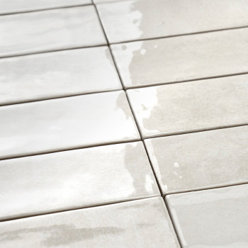 Los azulejos cerámicos rectangulares están dispuestas en una cuadrícula, reflejando la luz, creando una superficie brillante y c