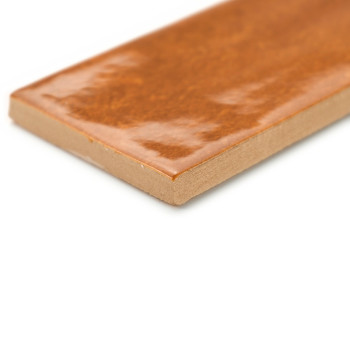 Un azulejo marrón rectangular, brillante, se asienta con su borde visible, sobre un fondo blanco, resaltando su superficie lisa 