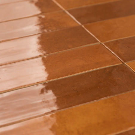 Des carreaux marron rectangulaires sont adjacents, réfléchissant la lumière sur une surface brillante, disposés en rangées horiz