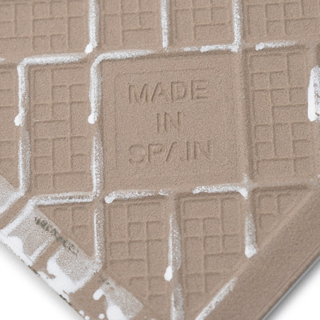 Eine strukturierte Fliese weist geprägte Gittermuster und den Text „MADE IN SPAIN“ in der Mitte auf, umgeben von weißen Rändern.
