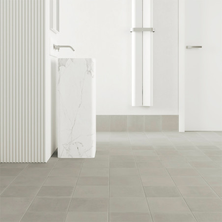 Los azulejos cuadrados cubren el piso de un baño minimalista, con un elegante lavabo con pedestal de mármol con un grifo moderno Los azulejos cuadrados cubren el piso de un baño minimalista, con un elegante lavabo con pedestal de mármol con un grifo moderno