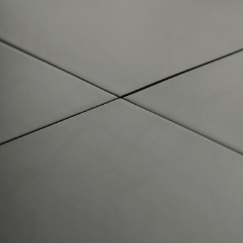 Les carreaux de céramique grises se croisent à angle droit, formant un motif en croix, dans un environnement lisse et uniforméme