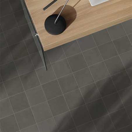 Un sol carrelé gris se trouve sous un bureau en bois moderne avec une élégante lampe noire, créant une atmosphère de bureau mini