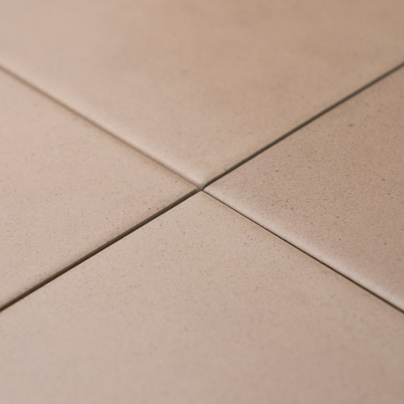 Four beige tiles intersect neatly, forming a small cross at their corners. They are set in a flat, even surface.