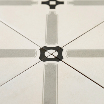 Un carreau de céramique présente un motif géométrique symétrique avec des lignes grises entrecroisées formant une croix, centrée