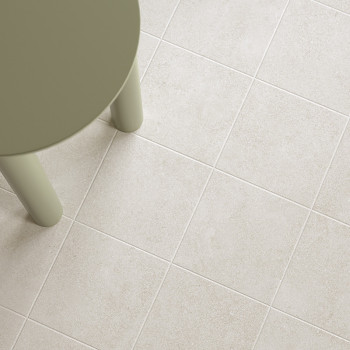 A round, olive-green table leg stands on a grid of light beige tiles, creating a modern, minimalist floor appearance.