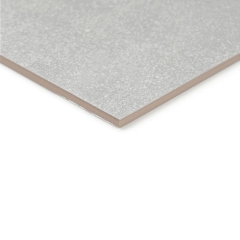 Un primer plano muestra Un azulejo cerámico gris rectangular con acabado mate, apoyada sobre una superficie blanca plana.