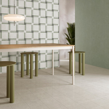 Una mesa de comedor moderna con taburetes cilíndricos verdes se encuentra sobre un suelo de azulejos claras, rodeada de azulejos
