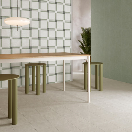 Een moderne eettafel met groene cilindervormige krukken staat op een lichte tegelvloer, omgeven door effen wandtegels met ruitmo
