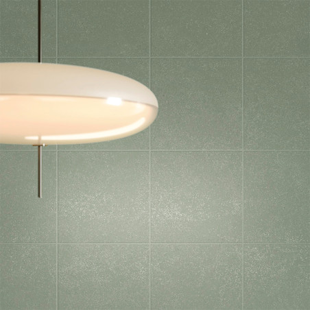 Una lámpara de techo redonda y blanca cuelga contra una pared lisa de azulejos de color verde apagado, proyectando un brillo cál Una lámpara de techo redonda y blanca cuelga contra una pared lisa de azulejos de color verde apagado, proyectando un brillo cál
