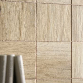 Carreaux avec un motif de grain de bois clair disposés en grille. le premier plan montre des objets cylindriques flous, éventuel