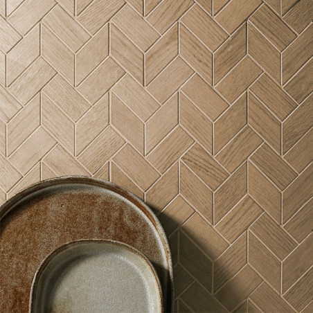 Light brown, wood-patterned tiles form a herringbone design on a wall. Two overlapping ceramic plates sit at the bottom left.