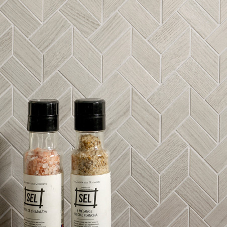 Duas garrafas de especiarias estão encostadas em uma parede de azulejos cinza claro em espinha. O texto nas garrafas diz `SEL,` 