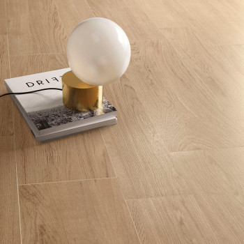 Eine kugelförmige Lampe ruht auf einem Buch mit dem Titel „DRIFT“, das auf einem hellen, holzgemusterten Boden platziert ist und