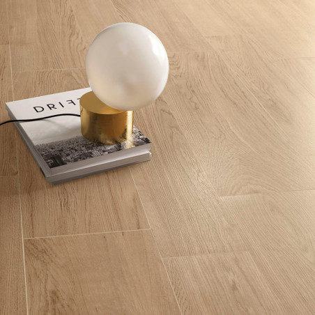 Une lampe sphérique repose sur un livre intitulé « DRIFT », placé sur un sol en bois clair, créant un cadre minimaliste et moder